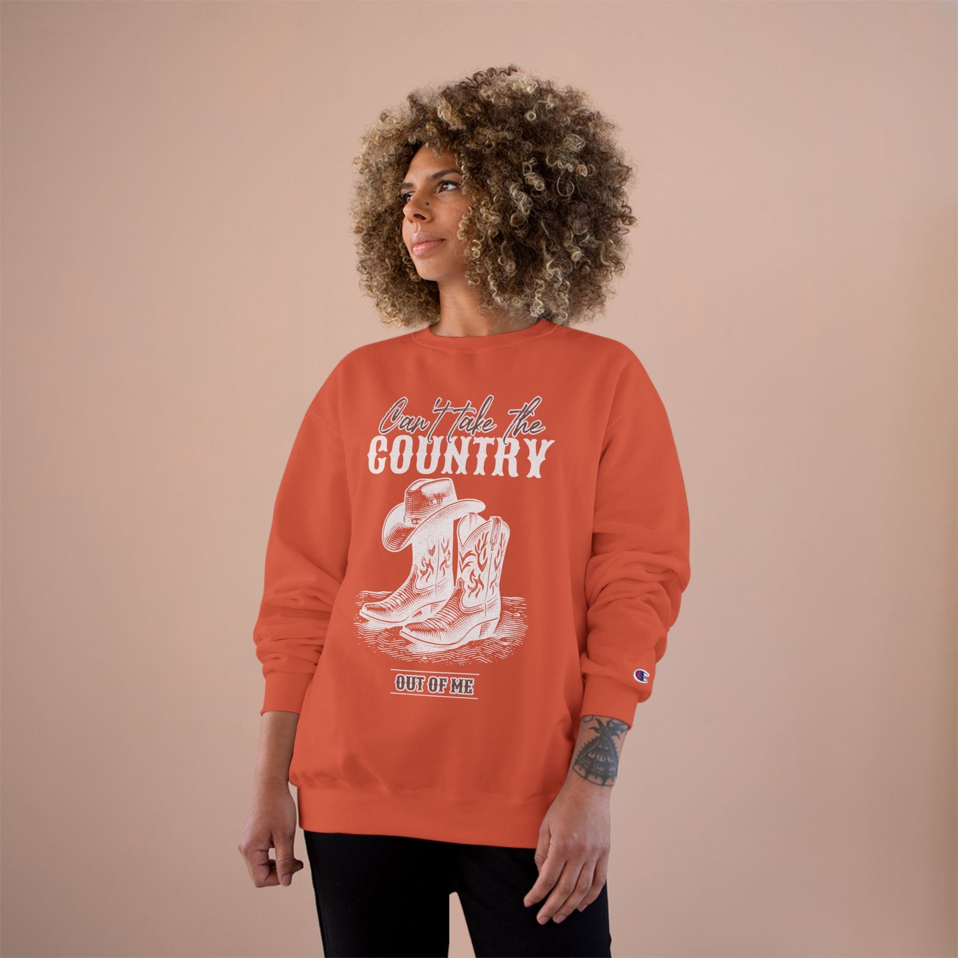 Person wearing an orange sweatshirt with a graphic design on a beige background